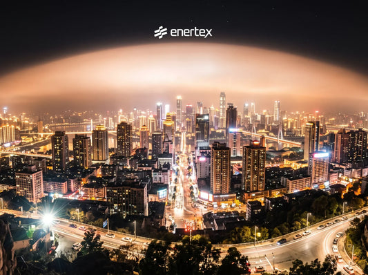 Una vista panorámica nocturna hiperrealista del horizonte de una gran ciudad. El denso paisaje urbano está repleto de rascacielos y calles intensamente iluminados con luces de color ámbar y blanco frío, creando una fuerte resplandor luminoso (skyglow).